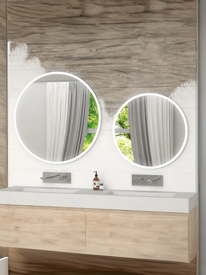 Double miroir rond rétroéclairé au-dessus d'un meuble double vasque en bois.