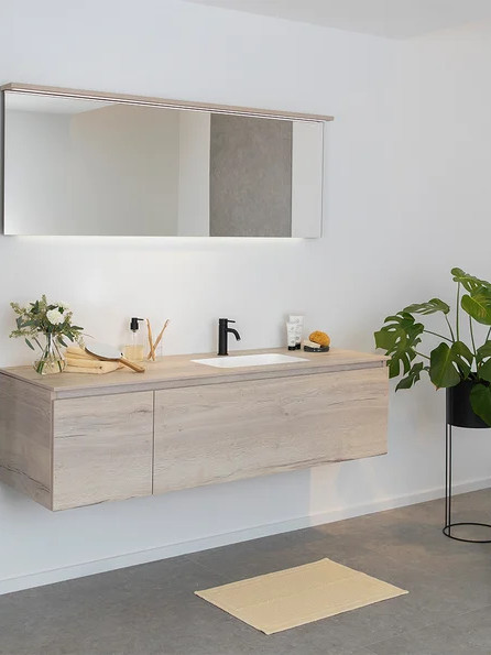 Wall-mounted bathroom column unit in light wood with matching vanity unit, wall mirror and clean finishes, ideal for a modern minimalist marble and wood bathroom