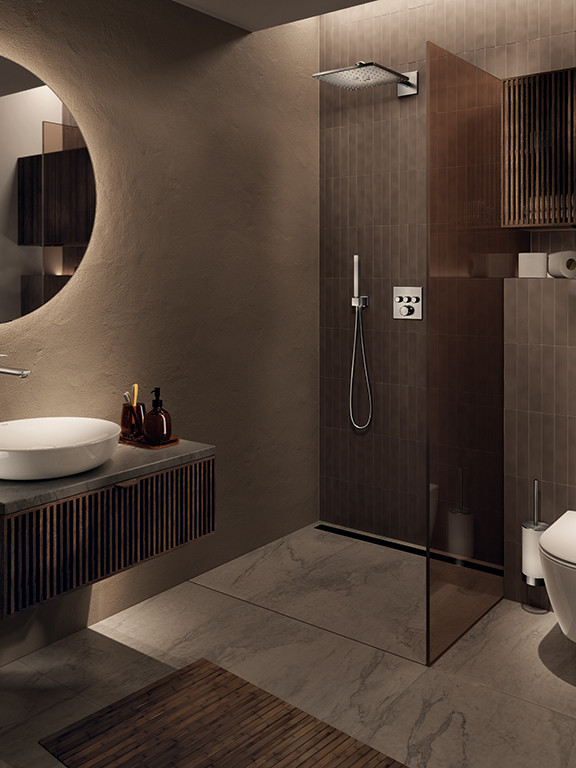 Salle de bain contemporaine avec douche à l’italienne, vasque suspendue et miroir rond rétroéclairé.