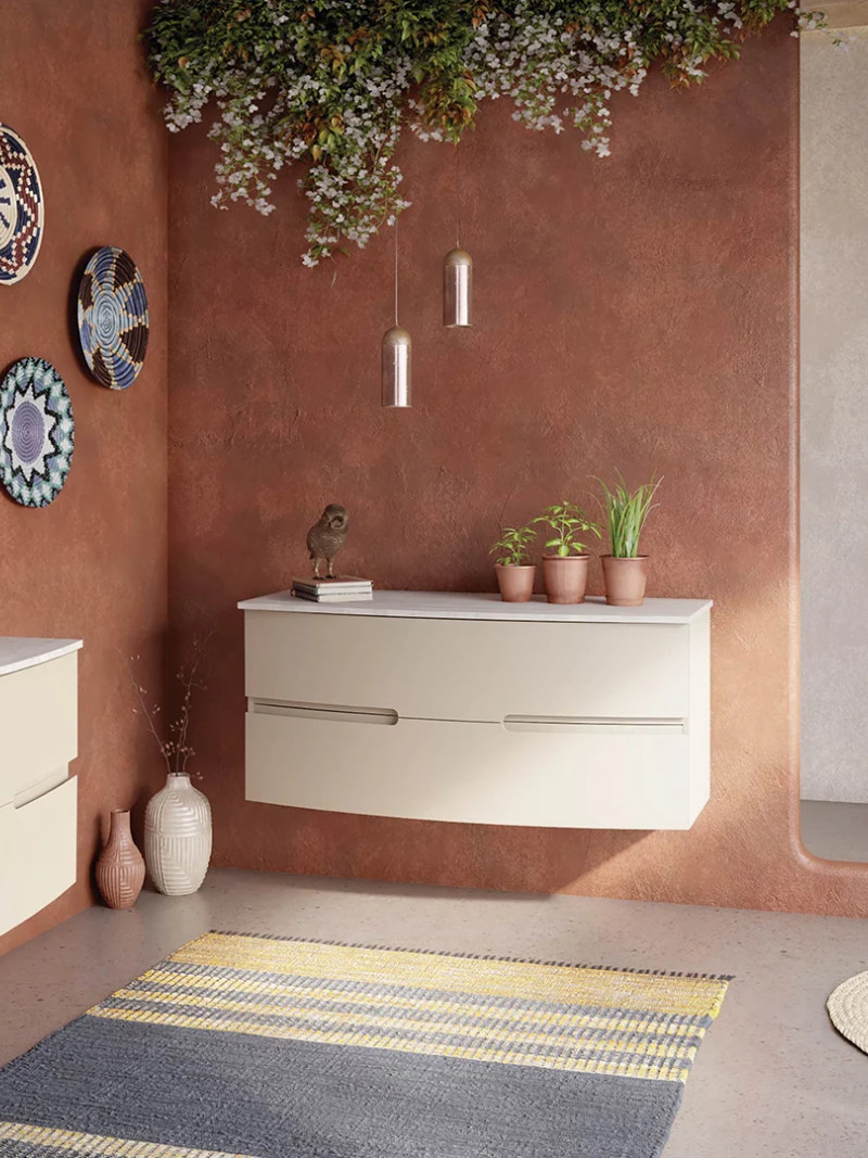 Salle de bains terracotta avec murs texturés, meubles suspendus crème et douche élégante.