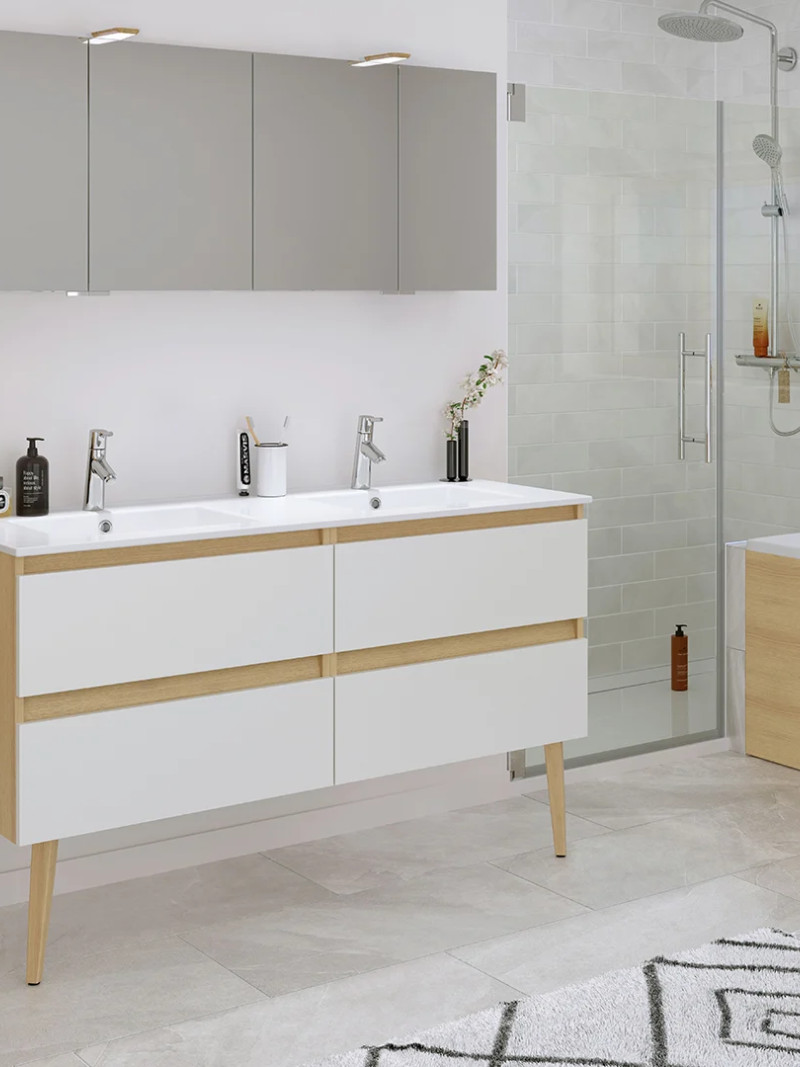A modern family bathroom with twin washbasins, a glass-enclosed walk-in shower, a bath and light-coloured wooden storage units.