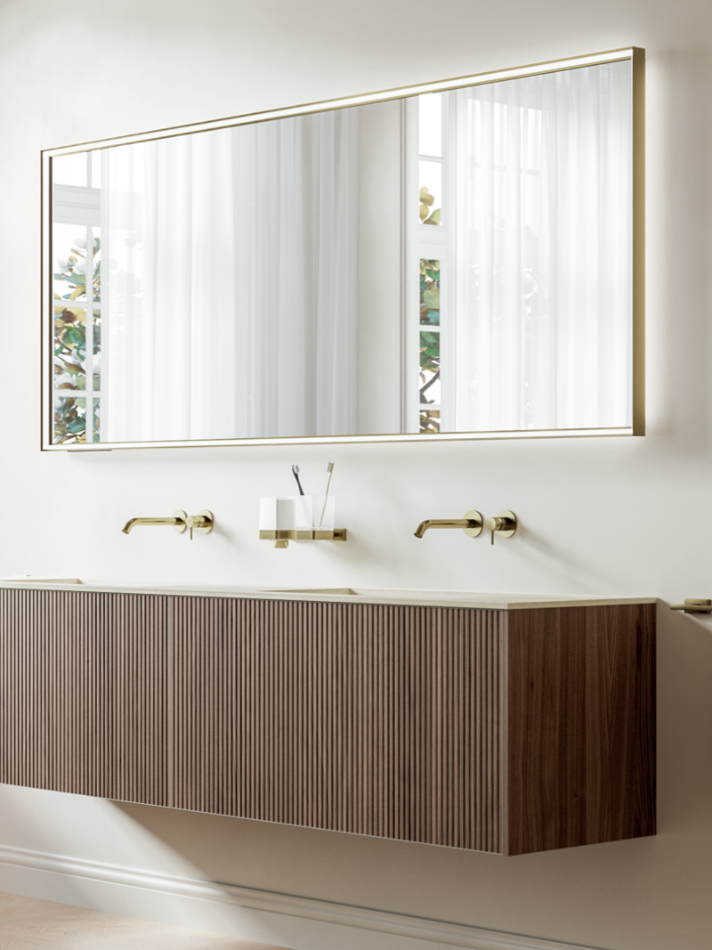 Meuble double vasque suspendu en bois rainuré avec plan blanc et robinetterie murale dorée dans une salle de bains lumineuse et élégante