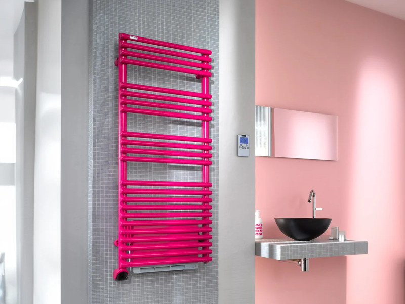 Sèche-serviettes rose fuchsia installé dans une salle de bains moderne avec vasque noire et murs pastel.